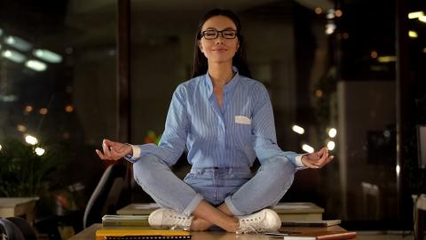Woman meditating with business supplies