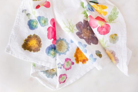 A white tea towel depicts colorful markings left after pounding flowers into fabric