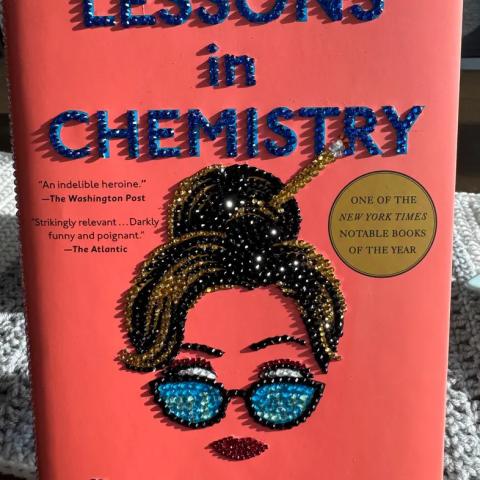 A book called Lessons in Chemistry is shown with rhinestones glued over the title and woman's face.