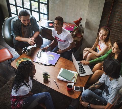 Teens hanging out together around a table.