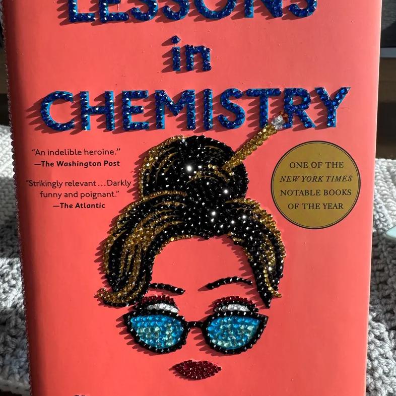 A book called Lessons in Chemistry is shown with rhinestones glued over the title and woman's face.